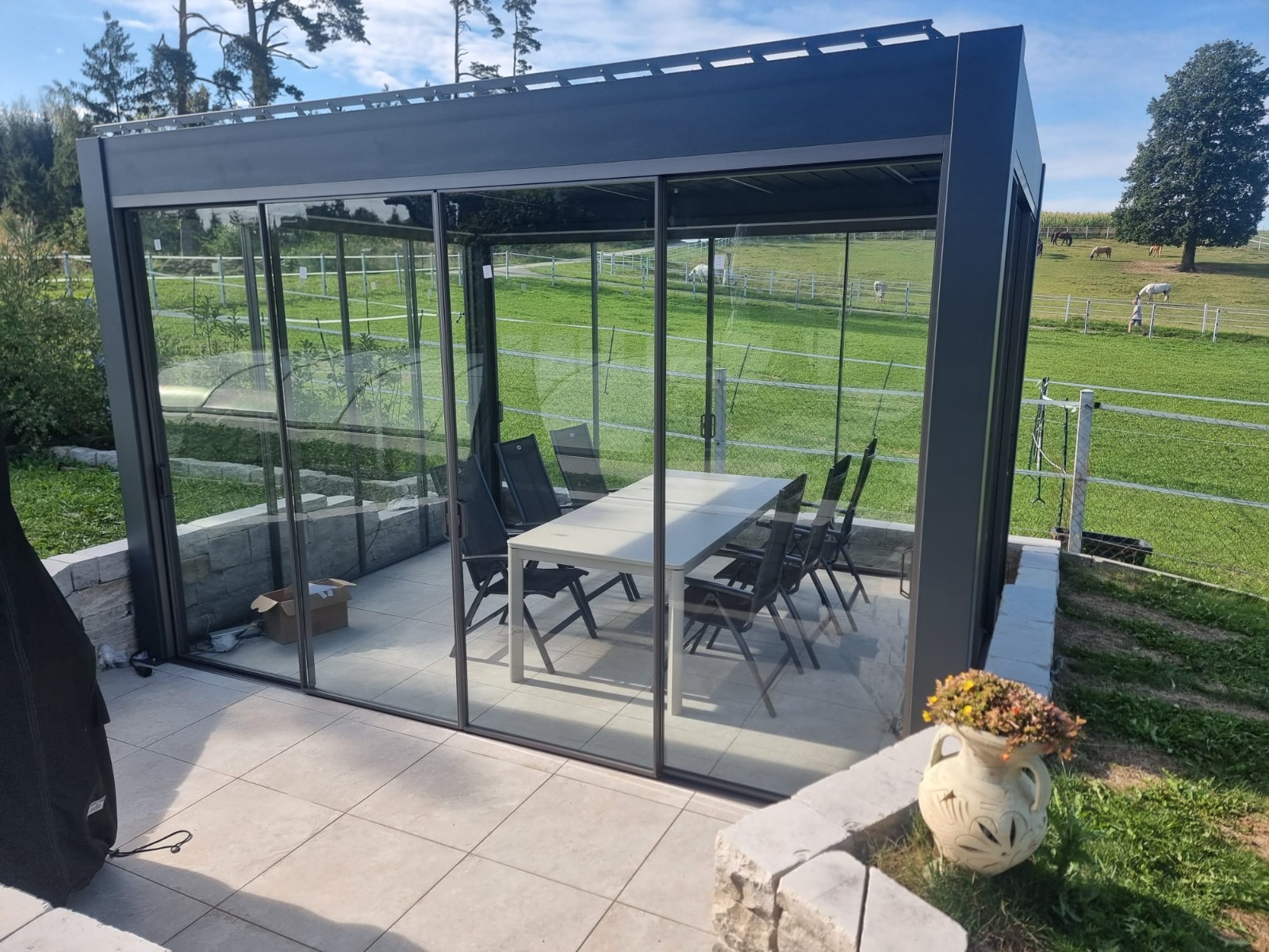 Pergola mit Lamellendach und rahmenloser Schiebeverglasung auf einer Terrasse